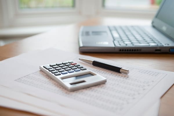 Mesa con documentos, una calculadora y notas